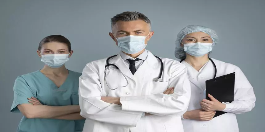 Healthcare, medical staff concept. Portrait of smiling male doctor posing  with folded arms, grey Stock Photo by Prostock-studio